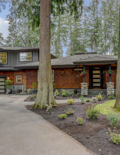 A home in the woods with a driveway and trees.